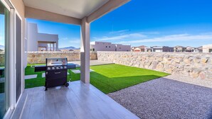 Eine moderne Außenpatio mit Grill, Steinwand und Blick auf die umliegende Nachbarschaft.