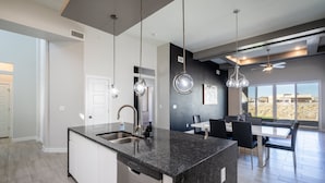 Eine moderne Küche mit Granit-Arbeitsplatten, Edelstahlgeräten und Pendelleuchten.