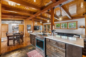 Una cocina amplia con vigas de madera, una isla grande con un lavaplatos y un comedor con sillas y mesa.