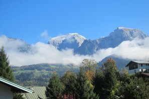 Eine Berglandschaft mit einem Haus im Vordergrund.