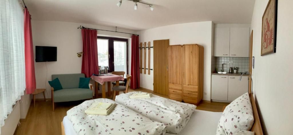Ein Zimmer mit einem Bett, einer Couch, einem Tisch, einem Fernseher und einer Küchenzeile.