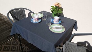 A table set with plates, cutlery, and a vase of flowers, with chairs around it. - Vacation apartment Kräuterbeet for 2 persons, 25 sqm, kitchenette, double bed (Inzell)