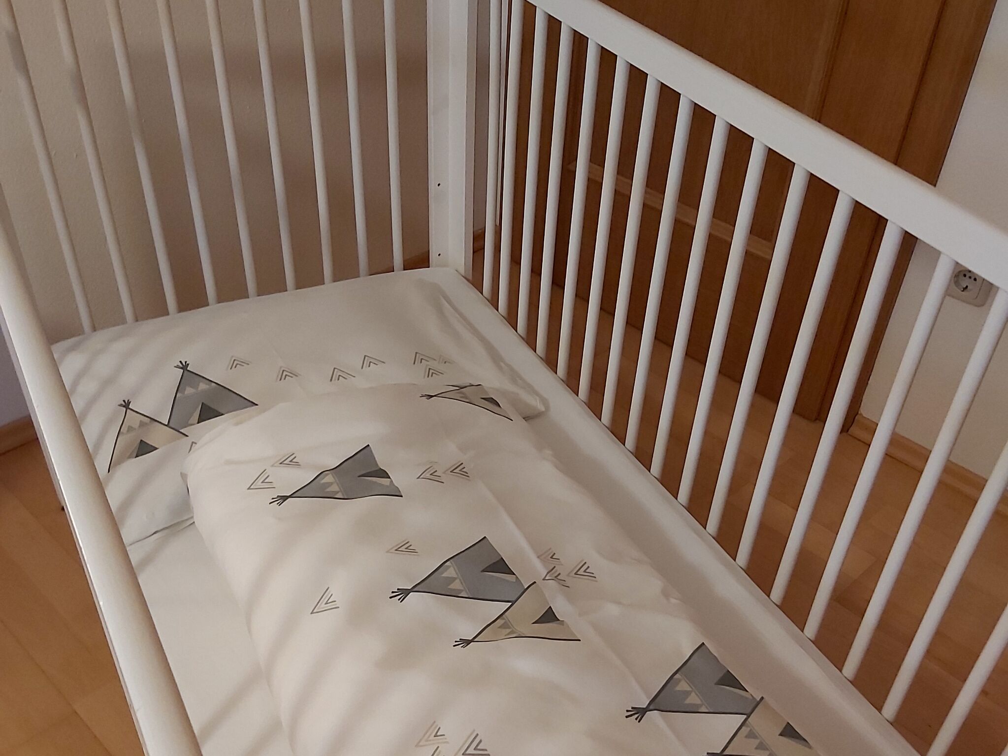 Una cuna blanca con un colchón que presenta diseños geométricos.