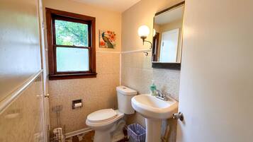 Une salle de bain avec des toilettes, un lavabo, une fenêtre et un miroir.