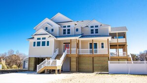 A multi-story house with a front porch, a garage, and a covered outdoor area. - Oceanside, Private Pool, ELEV, Hot Tub Rec Room, yard, SUN-SUN, WW865-This One's for You! (Corolla)