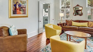 Una sala de estar con un sofá de cuero marrón, sillones amarillos, una mesa redonda de madera y una araña.