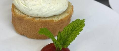 Un plato de postre con un pastelito cubierto de fresa y una hoja de menta como adorno.