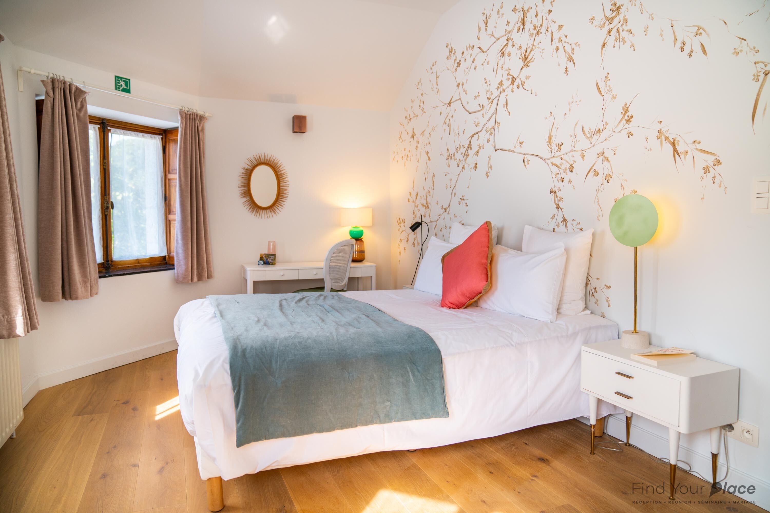 A bedroom with a bed, bedside table, lamp, and a window with curtains.