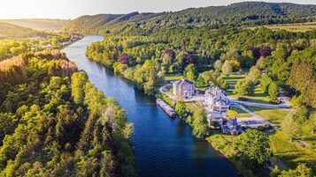 Une propriété située au bord de la rivière, comprenant une grande maison, un quai pour bateaux et de nombreux espaces verts.