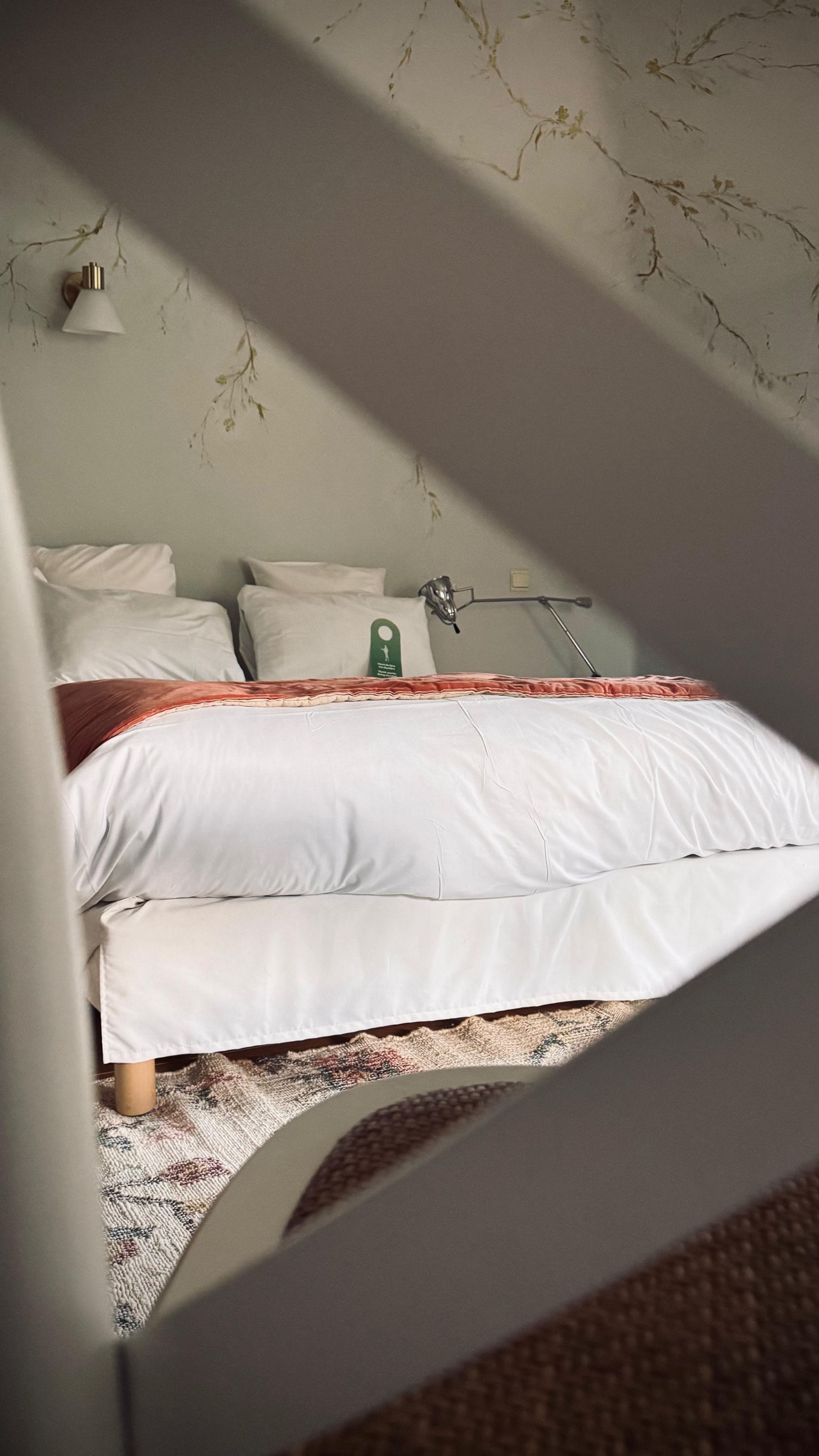 Un letto con biancheria bianca, un'etichetta verde e un tappeto decorato.