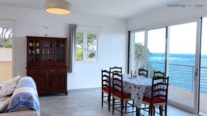 Ein Zimmer mit Esstisch, Stühlen, einem Schrank, einer Couch und Blick auf den Ozean.