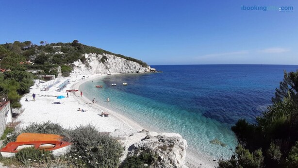 A beach with clear turquoise waters, white sandy shore, and rocky cliffs.
