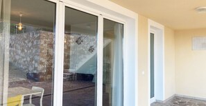 A modern interior with a stone wall, a staircase, and a glass door leading to an outdoor area.