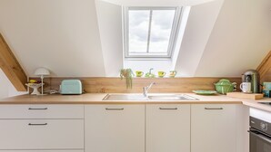 A modern kitchen with a skylight, wooden countertop, white cabinets, and a built-in oven. - Maison 1934 bnb (Colmar)