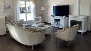 Un salon comprenant un canapé, des fauteuils, une table basse, une cheminée et un téléviseur.