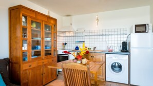 Une cuisine compacte avec un meuble en bois, un lave-linge et un coin repas comprenant une table et des chaises.