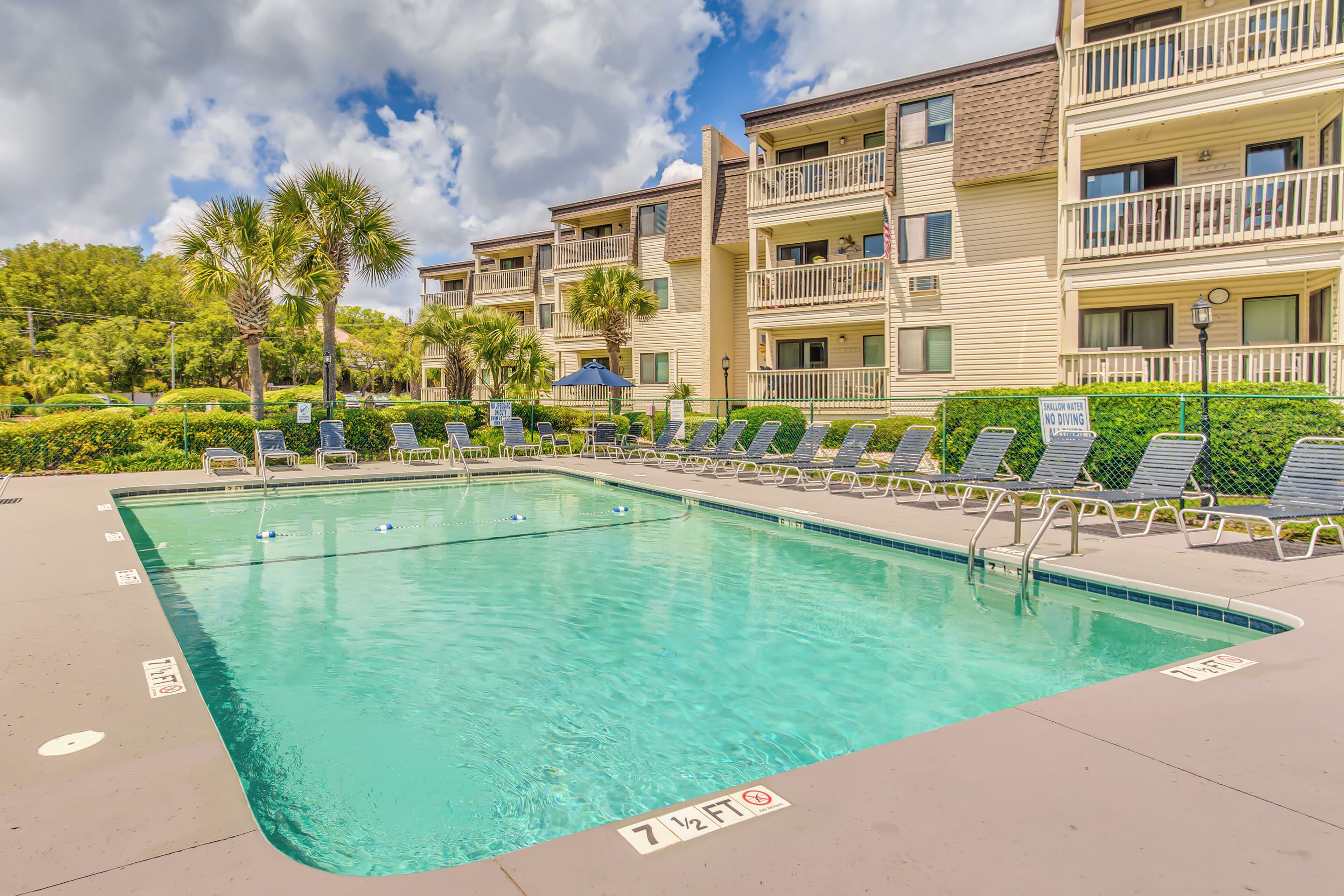 A swimming pool with lounge chairs and a sign indicating a 7 1/2 ft depth.
