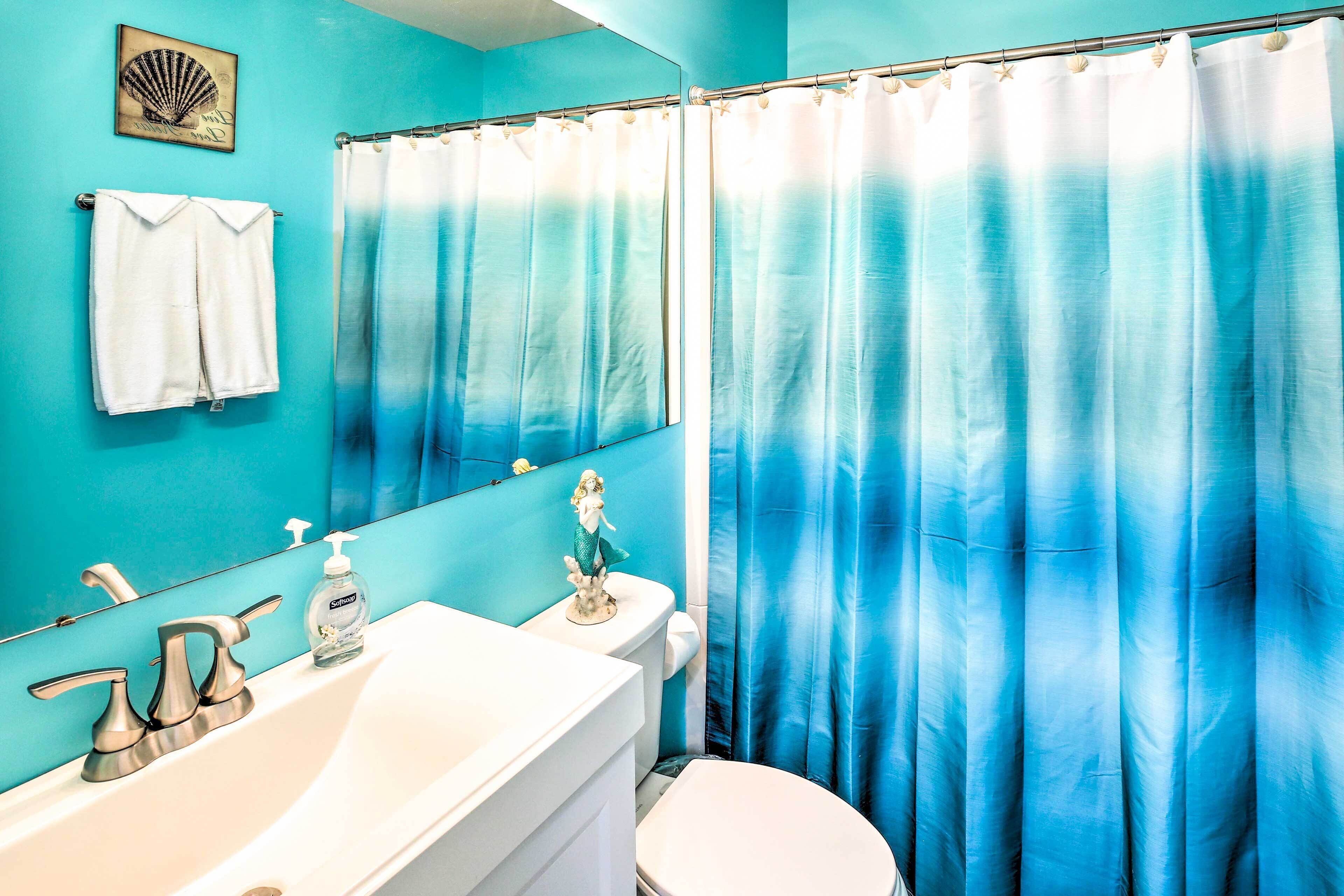 A bathroom with a blue gradient shower curtain, a white sink, a toilet, and a towel hanging on the wall.