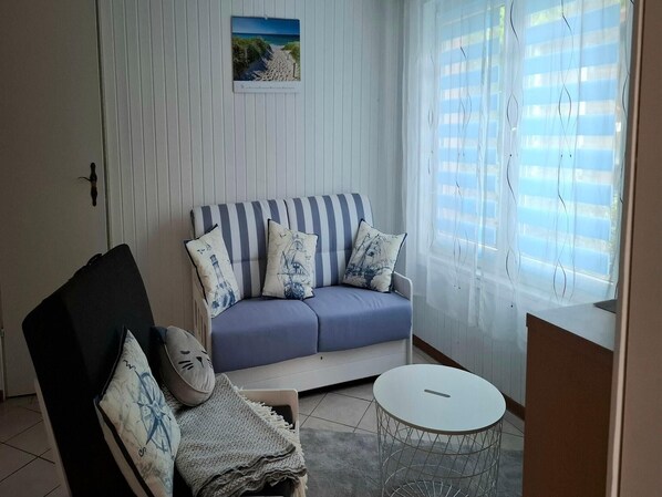 A living room with a striped sofa, a small round table, and a chair with a map cushion. - Romantic Retreat in Kröpelin (Kröpelin)