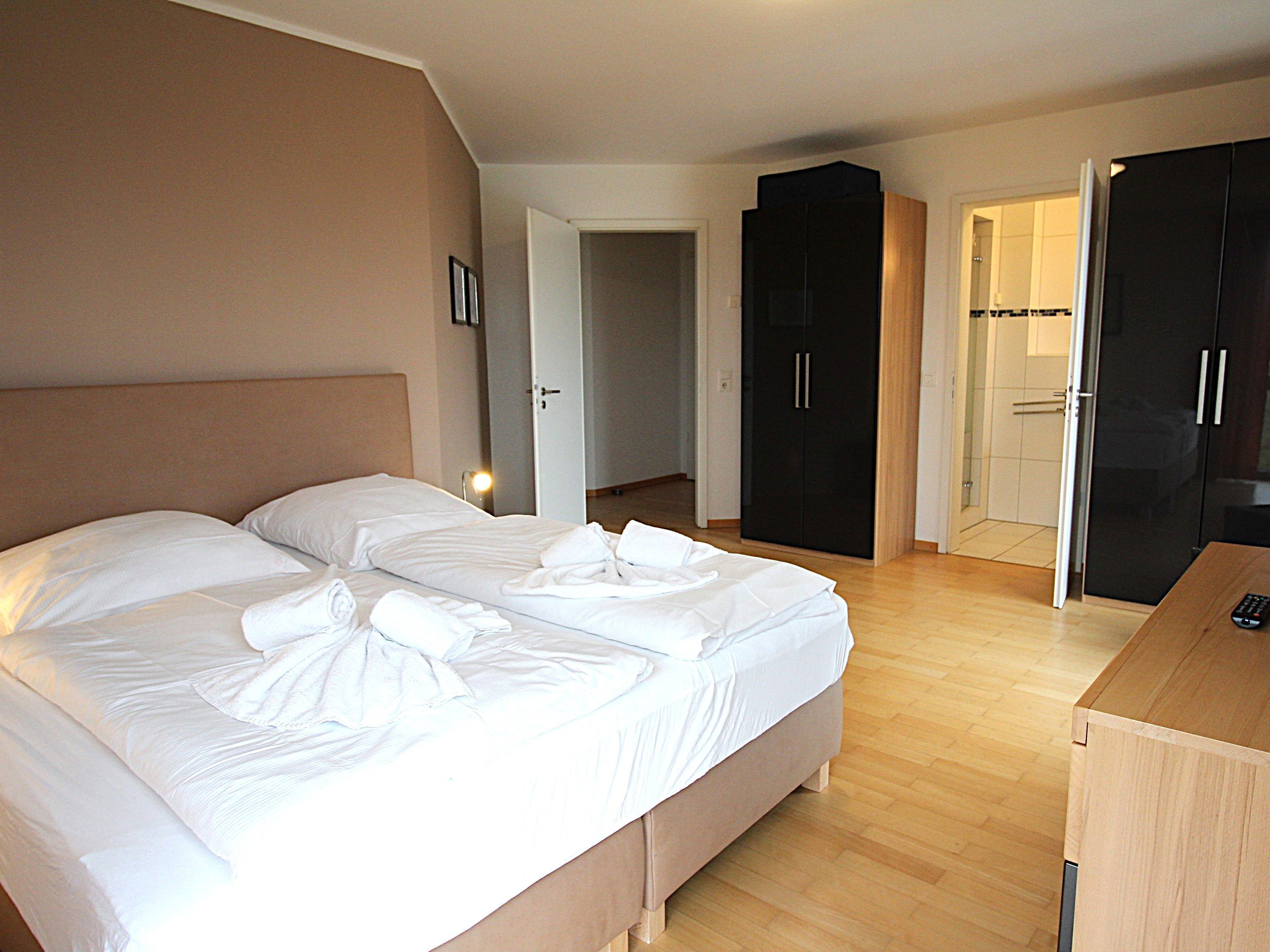 Habitación de hotel con dos camas, un armario y un escritorio.