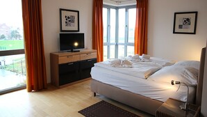 Ein Hotelzimmer mit Bett, Fernseher, Kommode und einem Fenster mit Vorhängen.