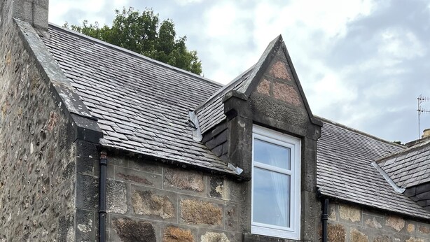 A stone building with a sloped roof, two windows, and a green door. - Luxury cottage in the heart of Craigellachie (Craigellachie)