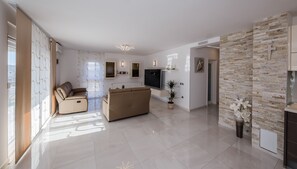 Una sala de estar moderna con un sofá color beige, un televisor de pantalla plana y una pared de acento de piedra.