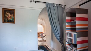 Ein Schlafzimmer mit Bett, einem Bild, einem Vorhang, einem Teppich und Aufbewahrungsboxen.
