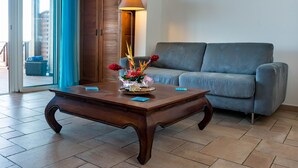 Una sala de estar con una mesa de centro de madera, un sofá gris, un armario de madera y una lámpara.