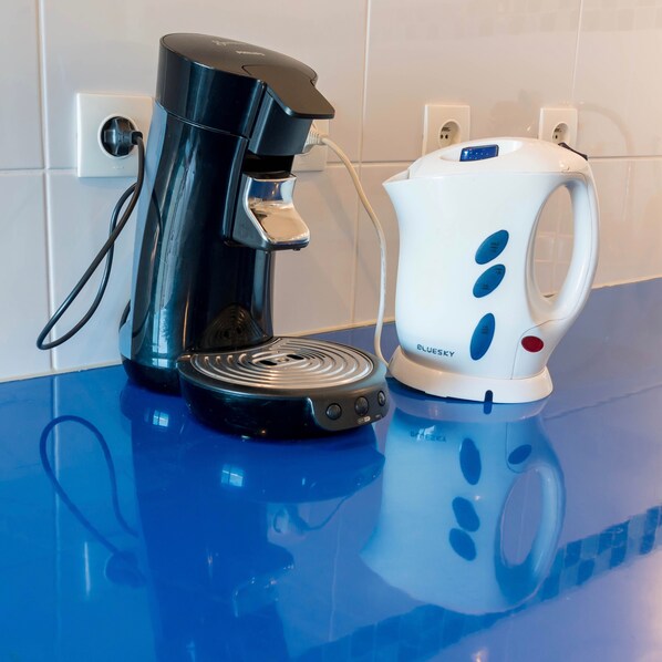 Une machine à café et une bouilloire sur un plan de travail bleu.