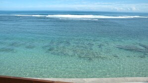 Vista despejada del océano con olas, una cubierta de madera y un borde de hormigón.