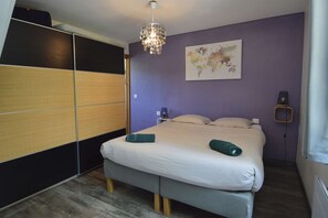 A bedroom with a bed, a bedside table, a lamp, a map on the wall, and a wardrobe. - Côté Mer - Private garden 200 meters from the beach (Ver-sur-Mer)
