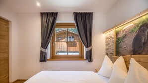 Un dormitorio con una cama grande, una ventana con cortinas, una puerta de madera y un cuadro colgado en la pared.