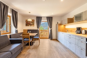 A modern kitchen with wooden cabinets, a dining area with a table and chairs, and a sofa.