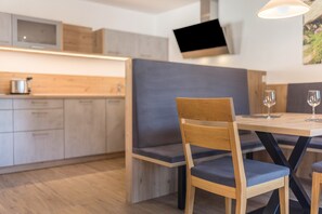Eine moderne Küche mit Holzausstattung, einer eingebauten Mikrowelle und einem flachbildfernseher an der Wand.