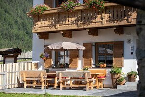 Ein Holzbalkon mit Blumenkästen, einem Holztisch und einer Bank sowie einem Holzzaun.
