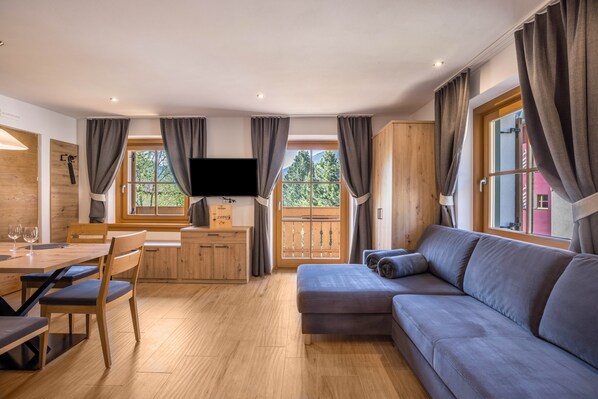 Ein modernes Wohnzimmer mit einem Holzesstisch, einer Couch und einem Fernseher.