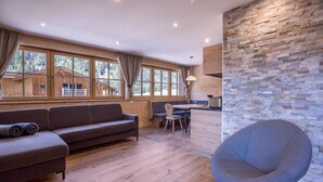 Un interior moderno con suelo de madera, un sofá, una zona de comedor y una pared de piedra.