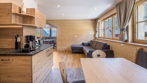 Una cocina moderna con armarios de madera, una mesa de comedor y un sofá empotrado.