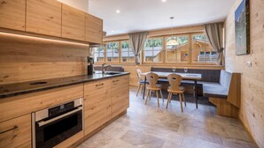 Una cocina moderna con armarios de madera, horno empotrado y una zona de comedor con bancos y sillas.