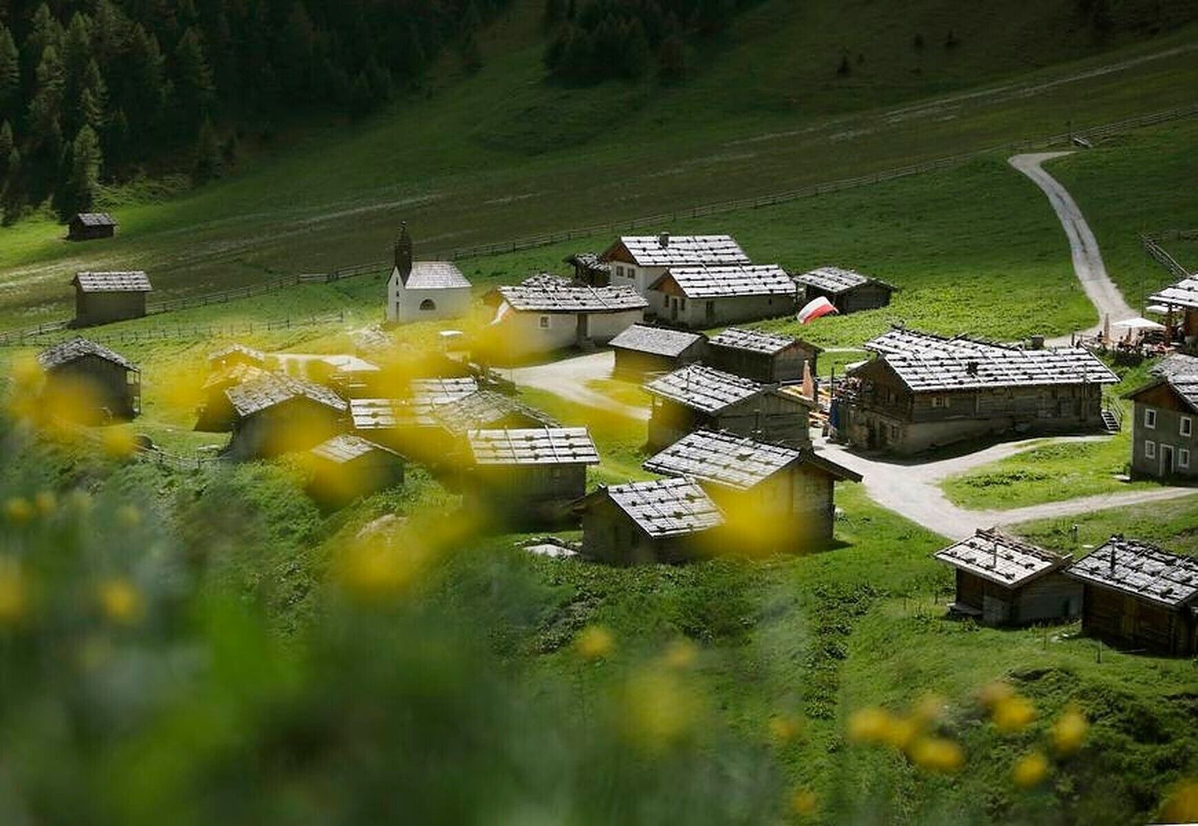 Un borgo rurale con case tradizionali, una strada centrale e una piccola chiesa.