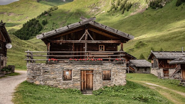 A rustic mountain cabin with a stone foundation, wooden exterior, and a balcony with flowers. - Cottage 'Lechnerhütte Fane Alm' with Mountain View, Wi-Fi & Terrace (Vals)