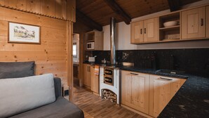 A wooden interior with a kitchen area, wooden cabinets, a microwave, and a fireplace. - Cottage 'Lechnerhütte Fane Alm' with Mountain View, Wi-Fi & Terrace (Vals)
