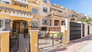 Un immeuble résidentiel doté d’un patio carrelé, d’une entrée sécurisée par un portail et de plusieurs balcons.