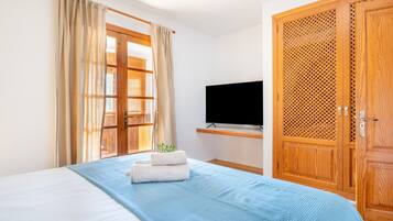 Une chambre d’hôtel avec un lit, une télévision, une armoire en bois et une fenêtre avec des rideaux.