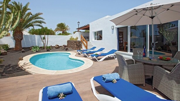 Un espace piscine aménagé avec des chaises longues, une table en verre et une pergola.