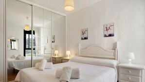 Ein Hotelzimmer mit einem großen Bett, einem Nachttisch mit Lampe, einem Spiegel und Bildern an der Wand.