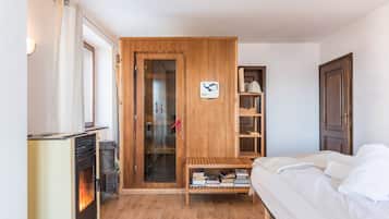 Ein Schlafzimmer mit einem Bett, einem Holzschrank, einem Bücherregal und einem Kaminofen.