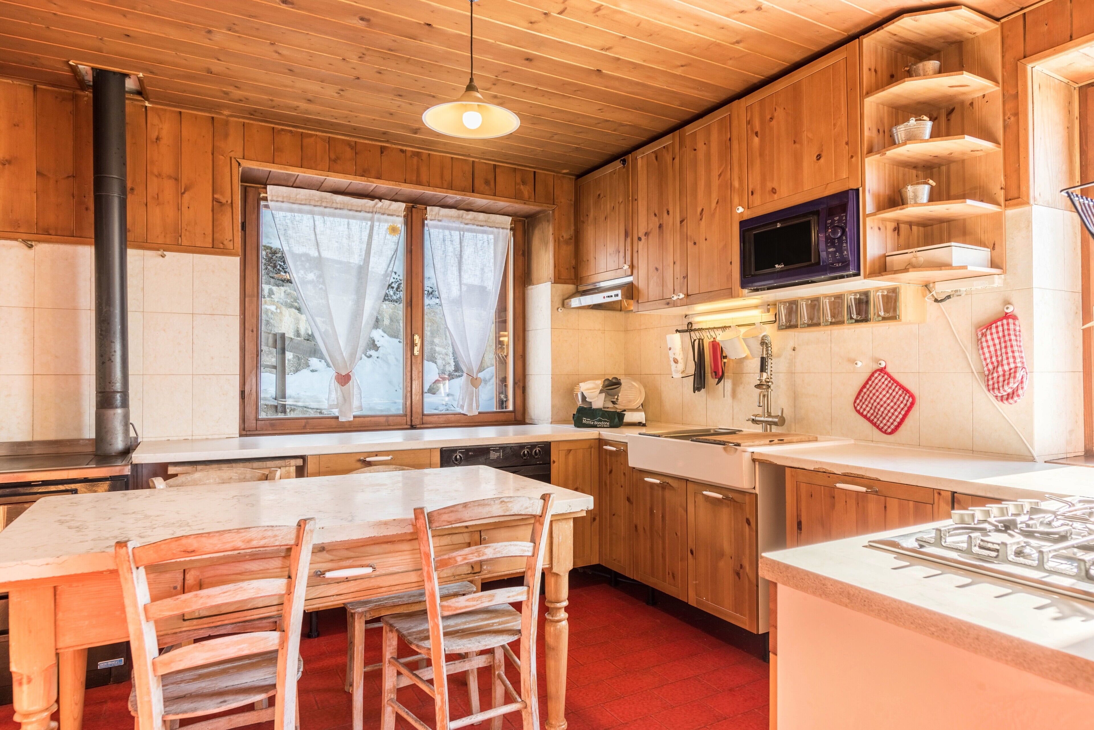 Een houten chalet inrichting met een keuken, eettafel, stoelen en een raam.