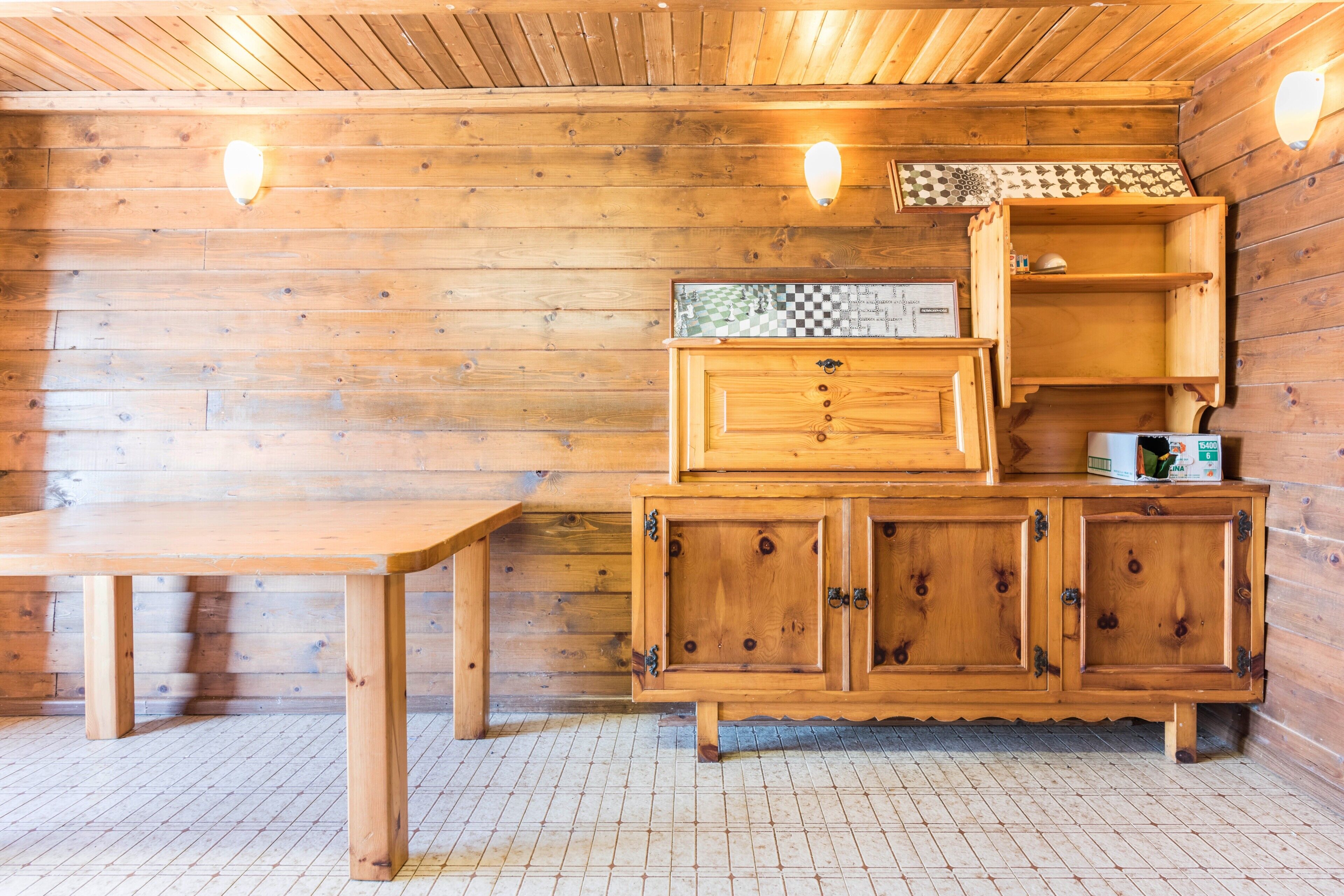 A wooden cabin interior with a wooden table, cabinets, and a checkered tile backsplash.